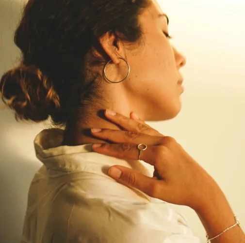 Woman pressing a hand to her neck to ease tension
